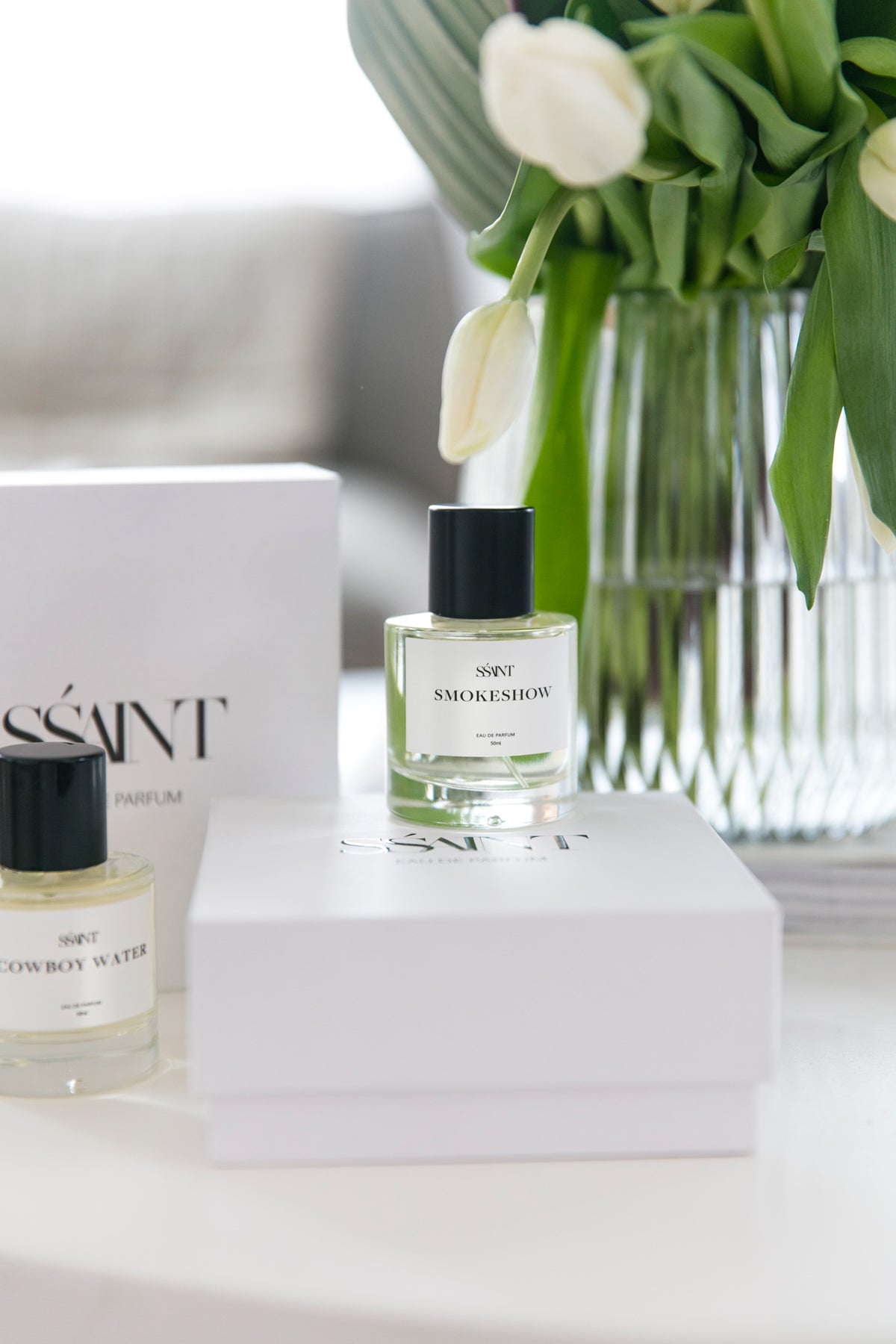Ssaint Perfume sitting on a gift box infront of fresh tulips