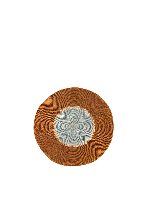 A round placemat with a beige and brown textured surface, handwoven from natural seagrass, displayed against a white background.