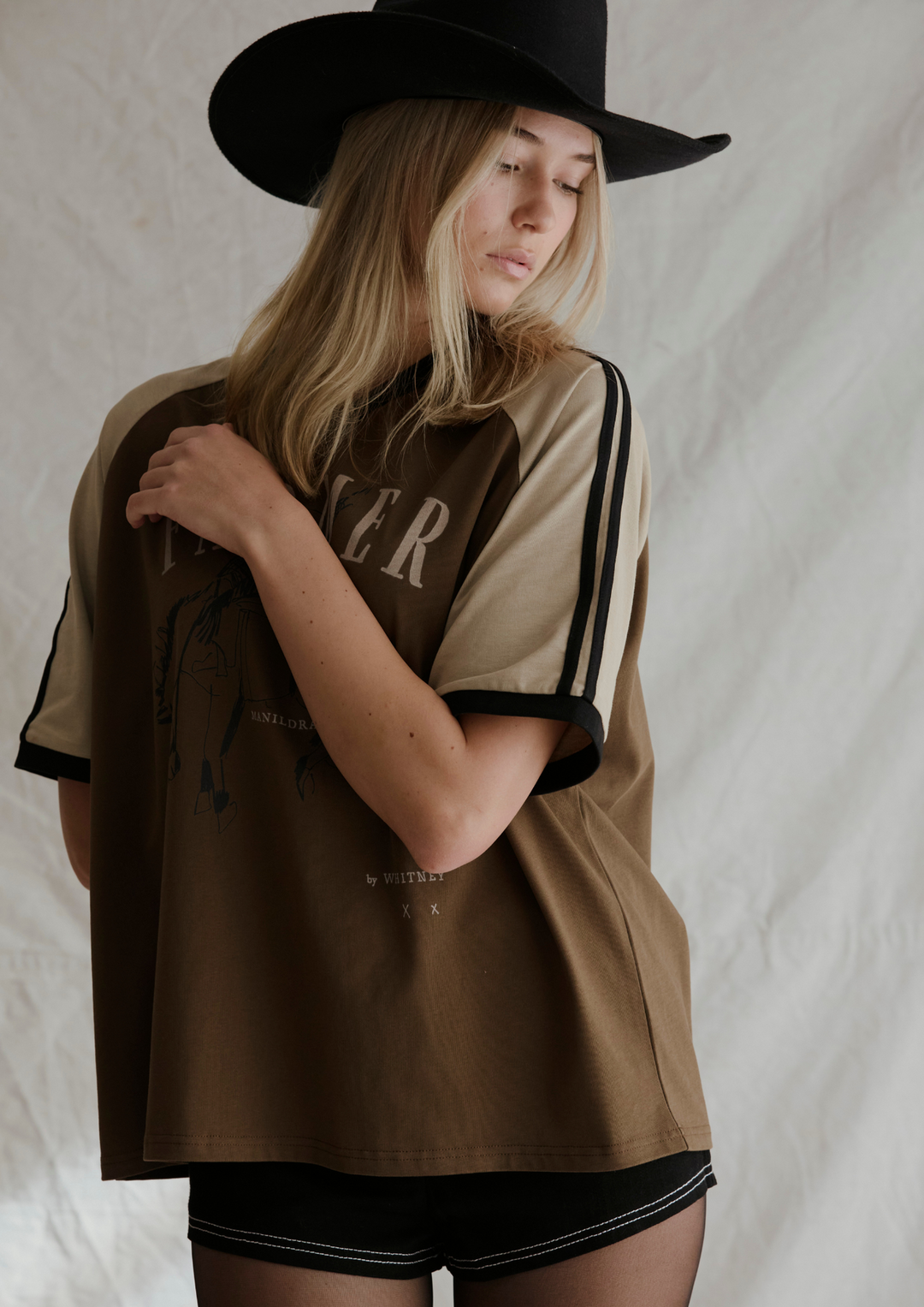 Person wearing a brown and beige sports jersey with 'RIDER' printed on it, standing against a plain background.