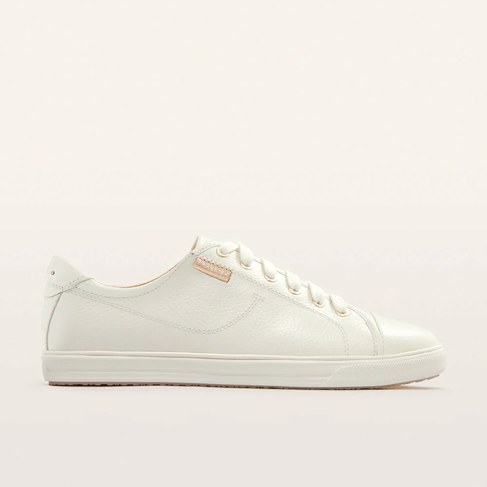 A white sneaker with gold accessories 